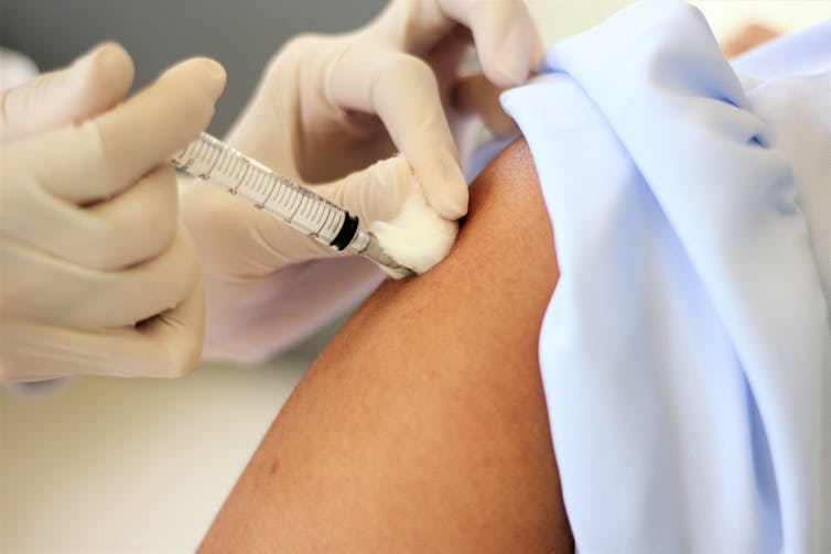 A person receiving an injection in their arm.