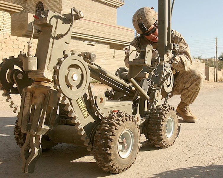 바퀴 달린 로봇은 전투 장비를 입은 군인이 돌보고 있습니다.