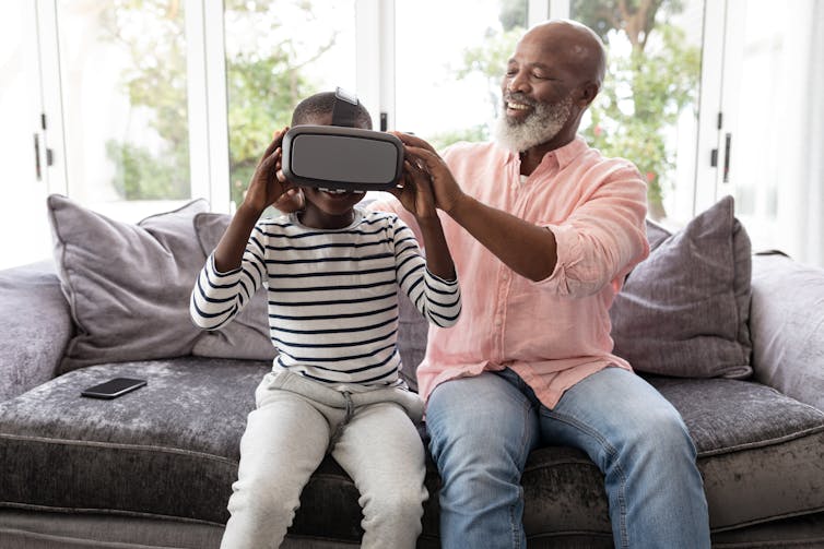 一名男子帮助一个孩子戴上虚拟现实头盔.