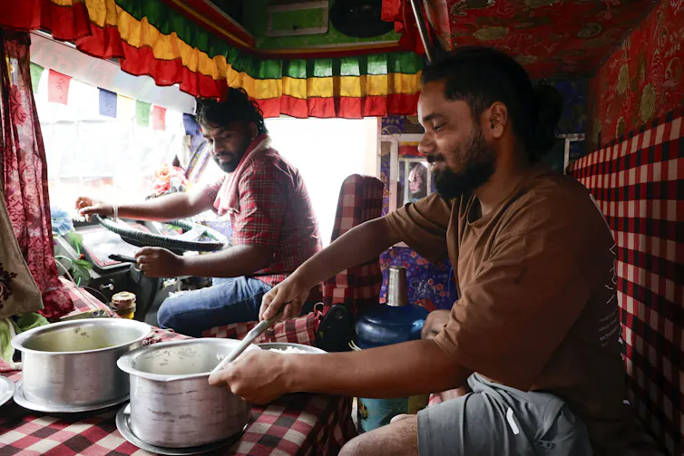 Two men prepare food in a truck after a flash flood.