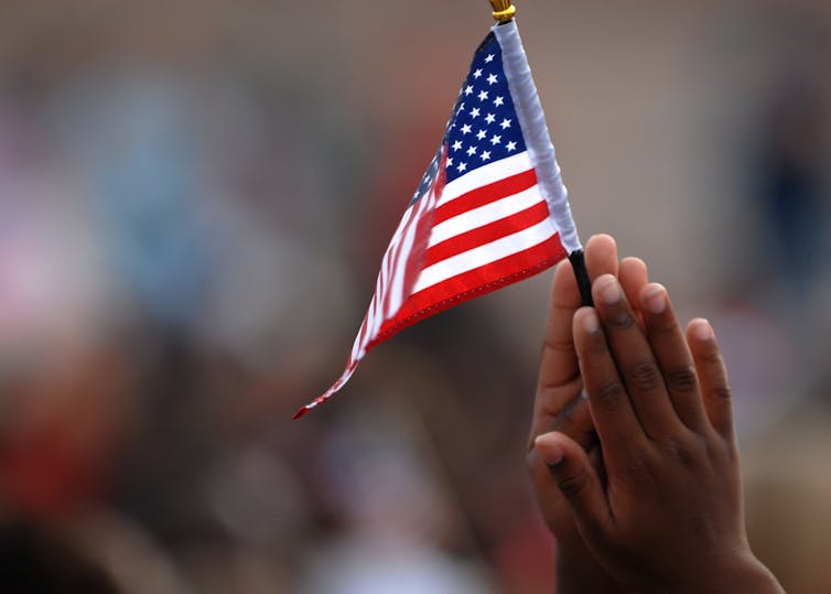 two hands holding small american flag