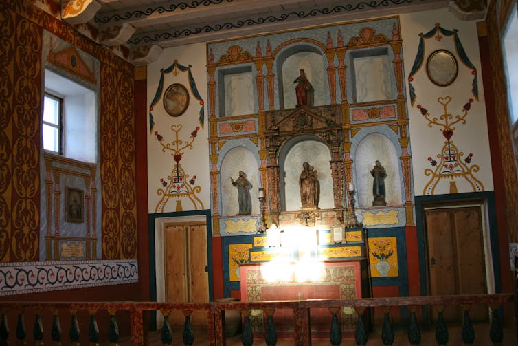 A ray of light illuminates golden touches on a tabernacle at the front of a church.