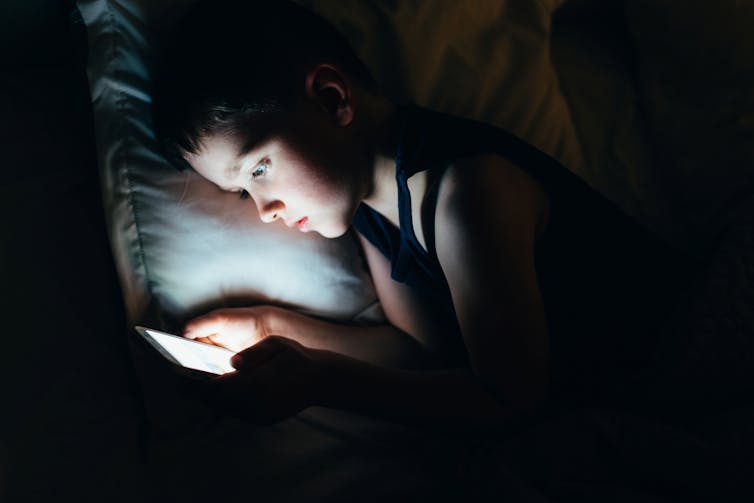 Young boy watching ipad at night in bed