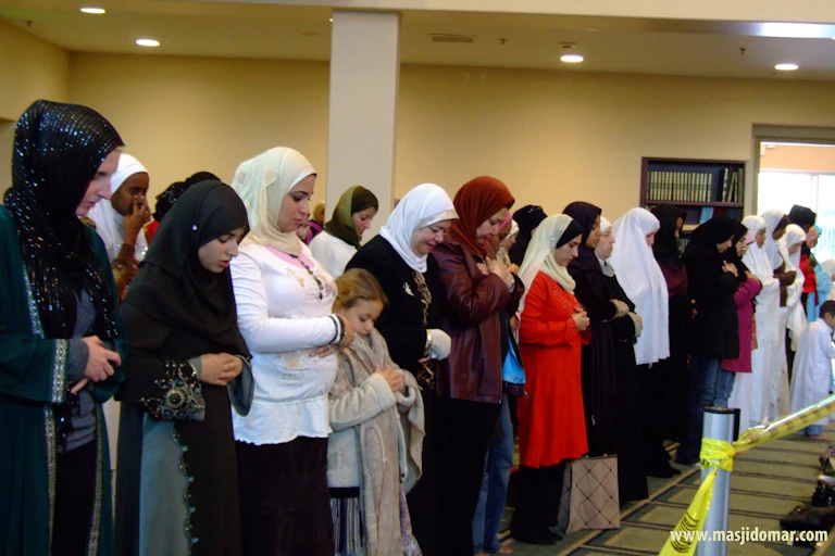 Women wearing headdresses praying with their heads bowed.