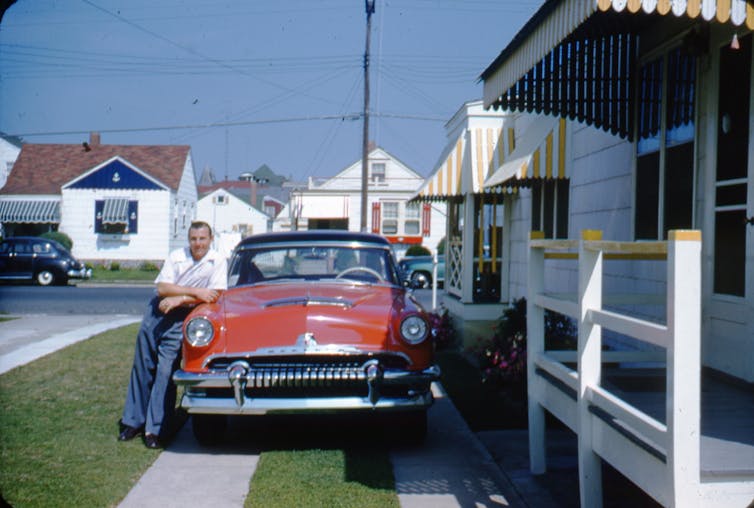 man-leaning-on-red-car