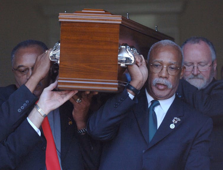 Tommie Smith, left, and John Carlos, right, who gave the historic Black Power salutes at the 1968 Olympics, reunite for the final time with the third man on the podium that year as they as they act as pallbearers for Peter Norman at his funeral in Melbourne, Australia in 2006. (AP Photo)