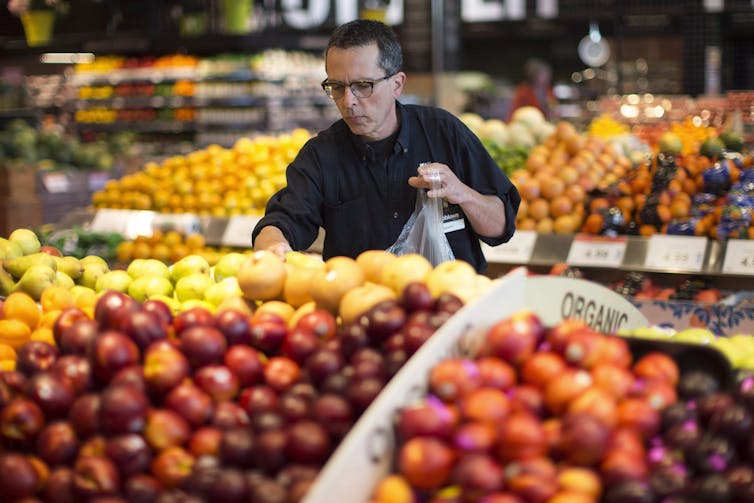 Grocery store employee gathers apples for an online order.