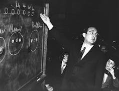 man pointing at a chalkboard with formulas