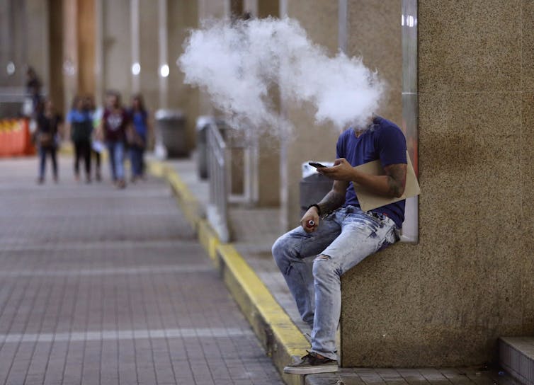 In this 2016 photo, a Filipino uses an electronic cigarette outside a mall in Manila. (AP Photo/Aaron Favila)