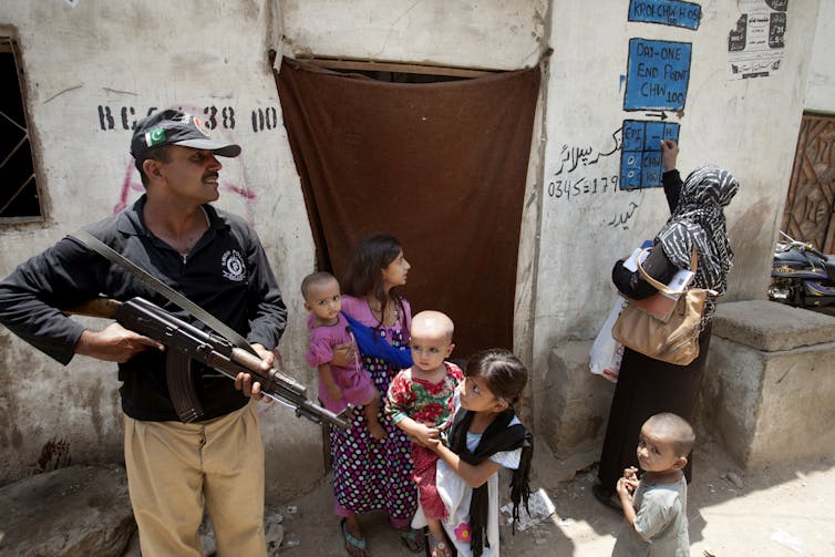With armed security, a Pakistani health worker marks a house after administering polio vaccine. (AP Photo/Shakil Adil)