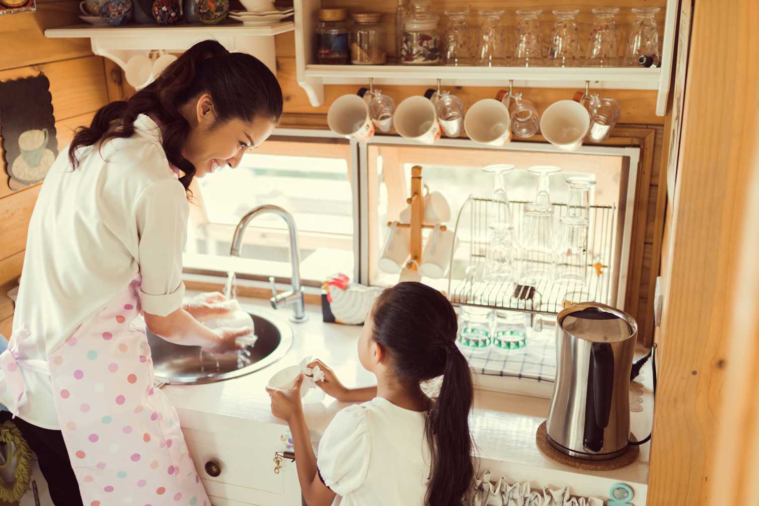 Японская мама на кухне. Помогать маме по дому. Мытье посуды. Мама моет посуду. Дочь помогает маме.