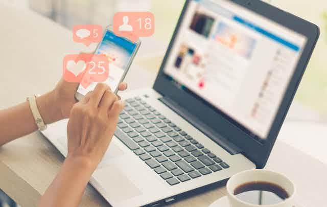 Image of someone holding a phone and receiving likes on social media.