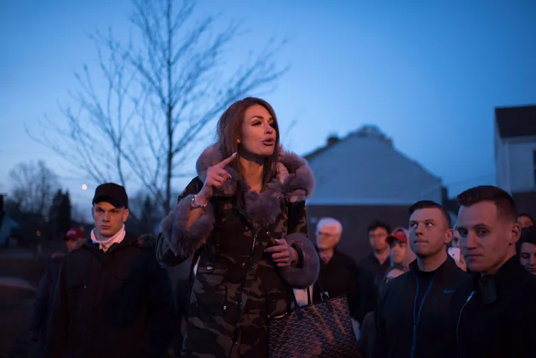 a woman with dark hair speaks at an outdoor event