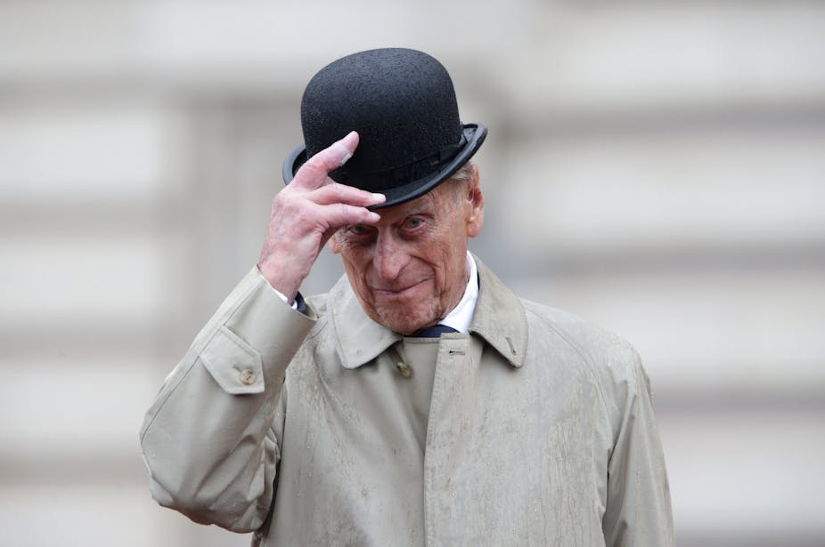 Prince Philip wearing and tipping a bowler hat.