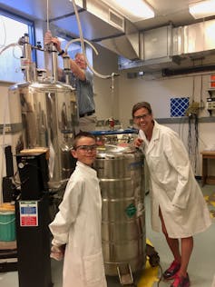 Woman and boy in lab coats next to helium tanks.