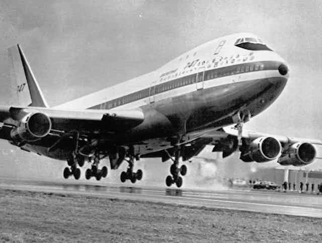 a large airplane begins ascent from runway with wheels inches above the ground