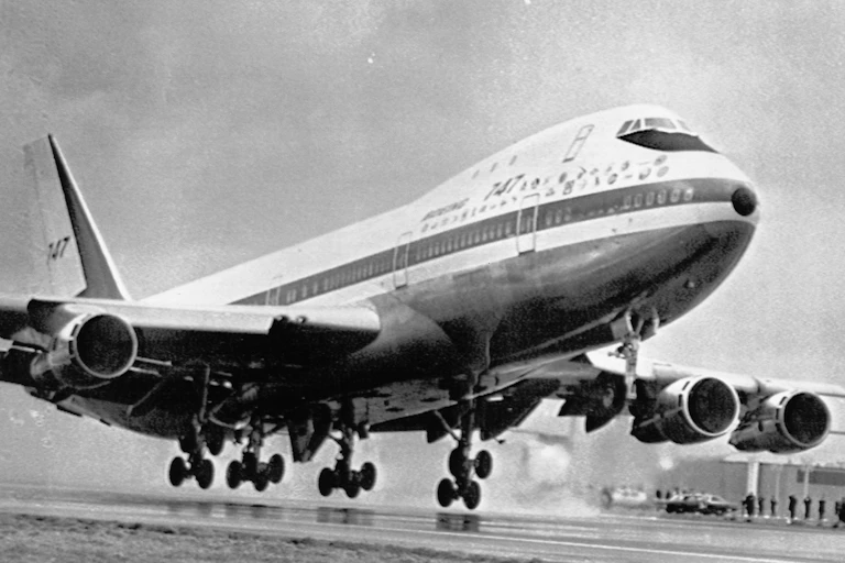 a large airplane begins ascent from runway with wheels inches above the ground