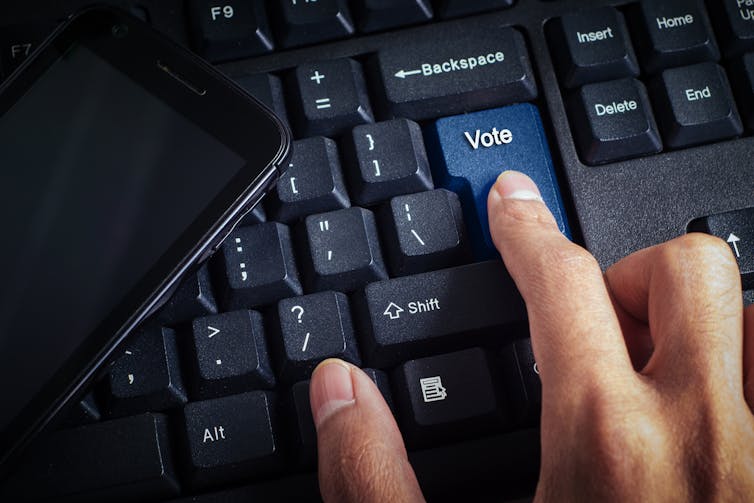 A person's hand on a keyboard with a vote button