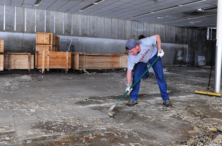 Person cleaning floor of abandoned home