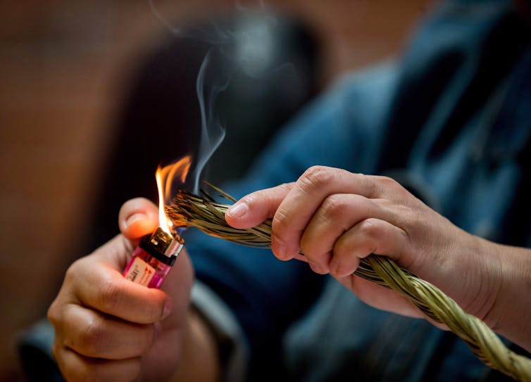 Evelyn Youngchief burns sweetgrass during a Coalition on Missing and Murdered Indigenous Women and Girls news conference, in Vancouver, B.C., in 2017. Sweetgrass is a healing herb, used in smudging, to cleanse and purify. THE CANADIAN PRESS/Darryl Dyck