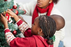 child decorating christmas tree