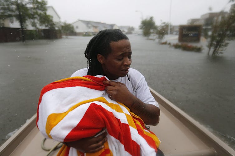 Demetres Fair holds a towel over his daughter, Damouri Fair, as they are rescued following Hurricane Harvey