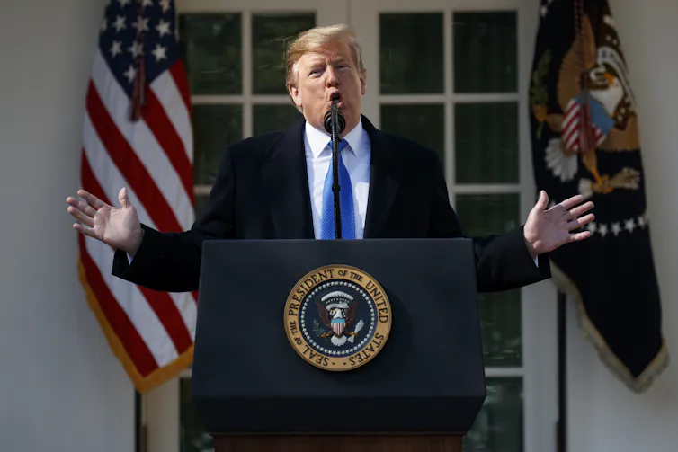 Former President Donald Trump speaking at a lectern bearing the presidential seal.