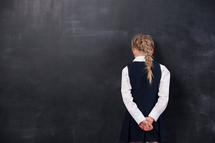 girl standing in front of a blank chalkboard