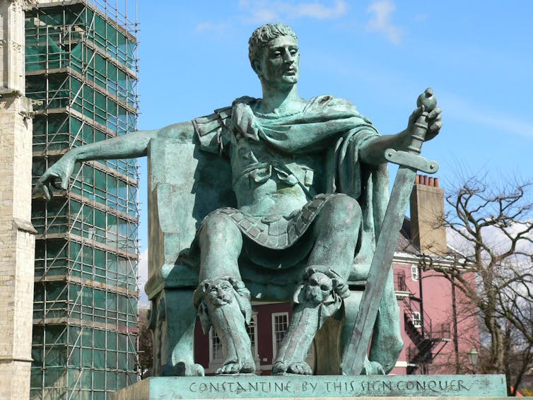 Large metal sculpture of the Emperor Constantine, seated, holding a sword.