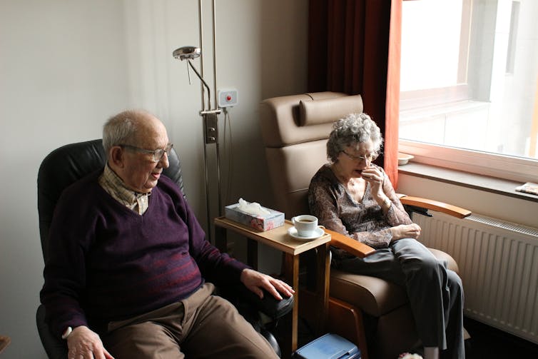 Image of elderly couple sitting in an aged care facility
