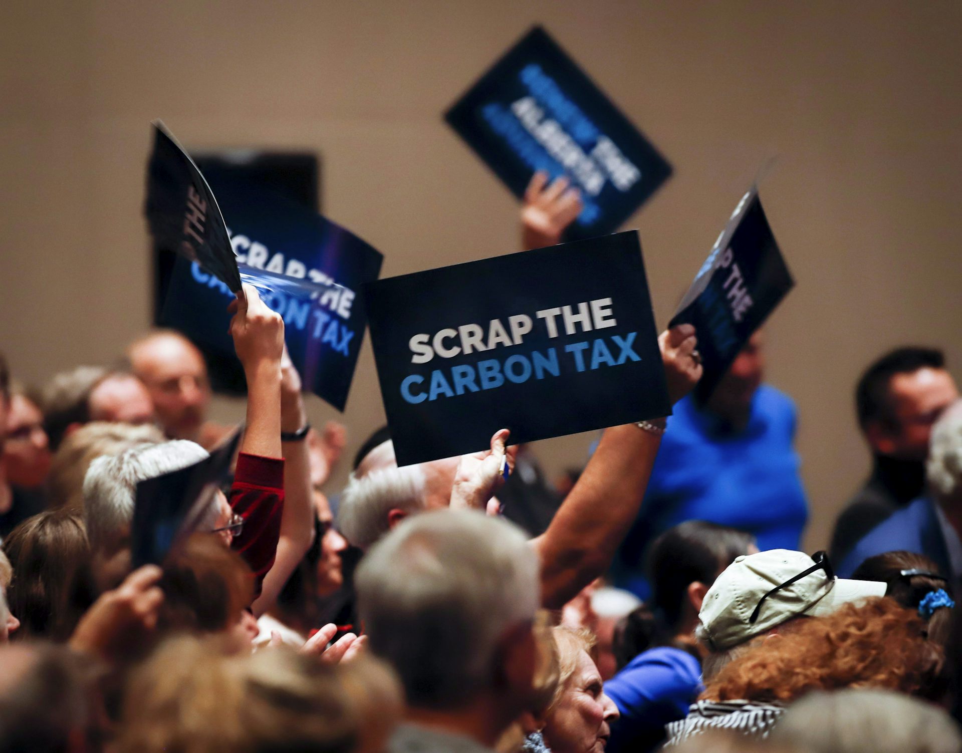 People wave signs reading Axe the Carbon Tax.