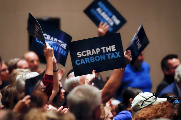 People wave signs reading Axe the Carbon Tax.