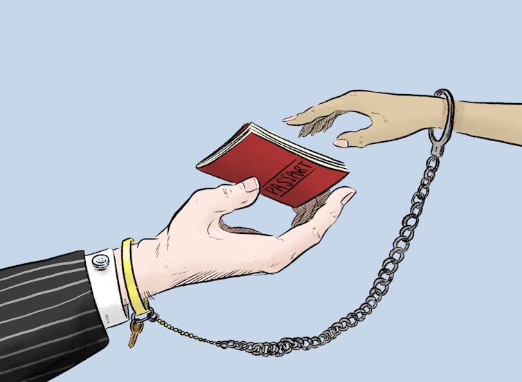 A white hand wearing a suit holds a passport out to a brown hand, which reaches for it. The brown hand is chained to the white hand, with a key hanging from the white hand’s wrist.