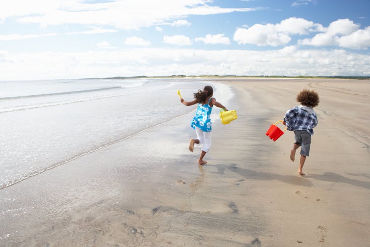 photo of two children running on a beach