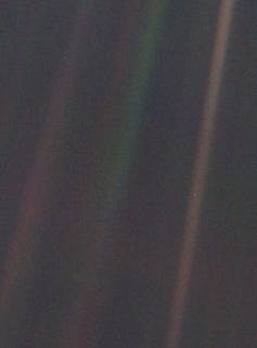 La Tierra desde el sistema solar, visible como un minúsculo punto azul pálido en el centro de la franja marrón situada a la derecha. NASA, Voyager 1