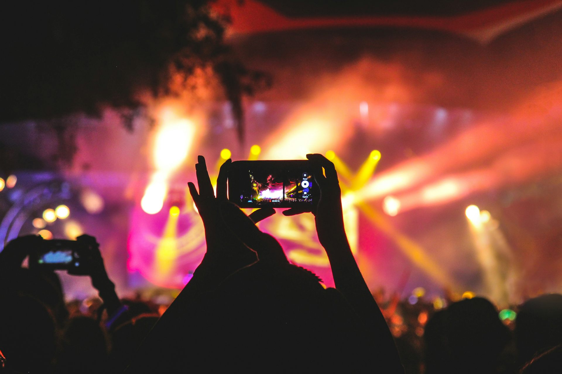 A person taking a photo on their mobile phone at a festival