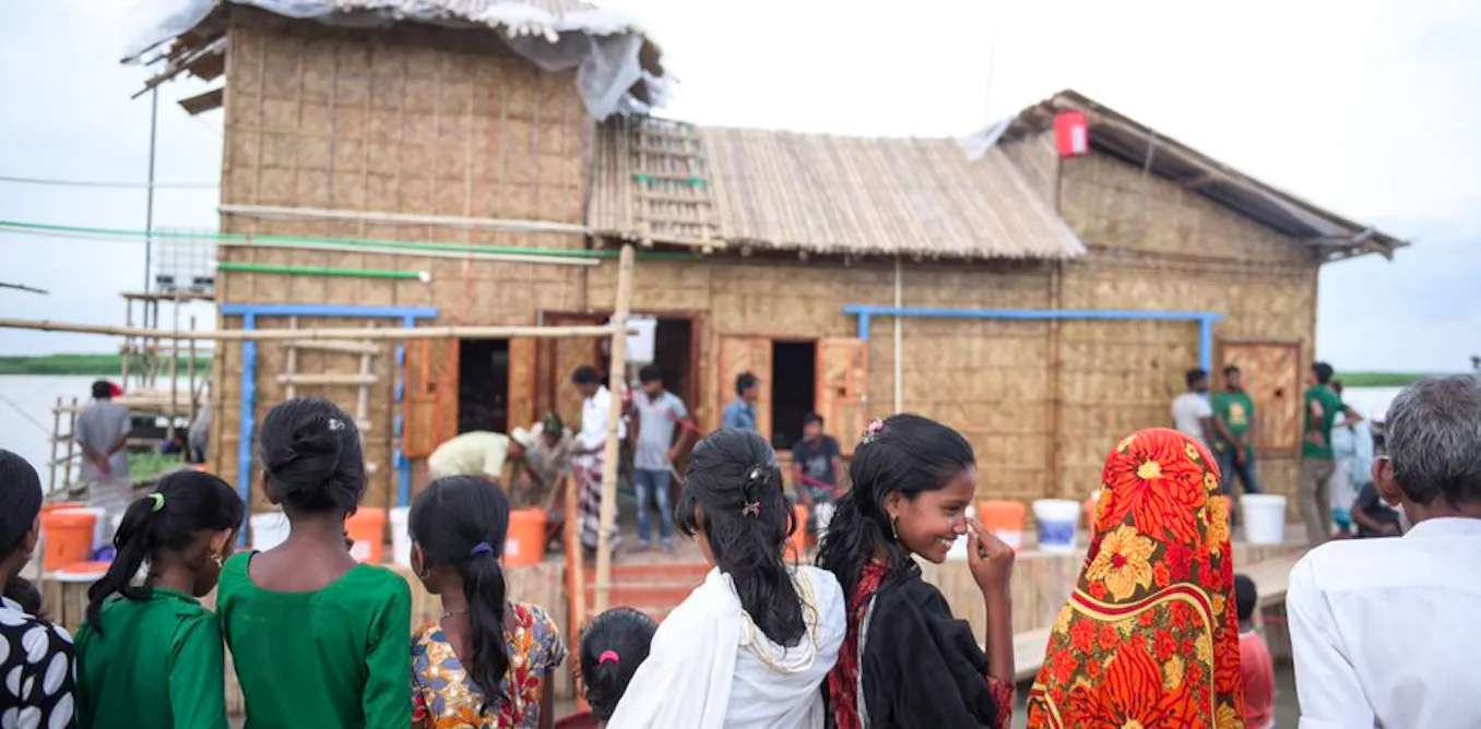 Community members gather around the Swapner Bari amphibious house under construction on the Balu River in Dhaka, Bangladesh