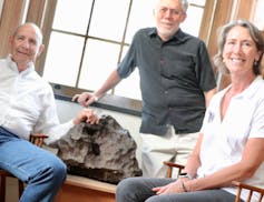 Drew Barringer (left), owner of Arizona meteor crater, his wife, Clare Schneider, and author William Herbst in the Van Vleck Observatory Library of Wesleyan University, where an iron meteorite from the crater is on display. W. Herbst