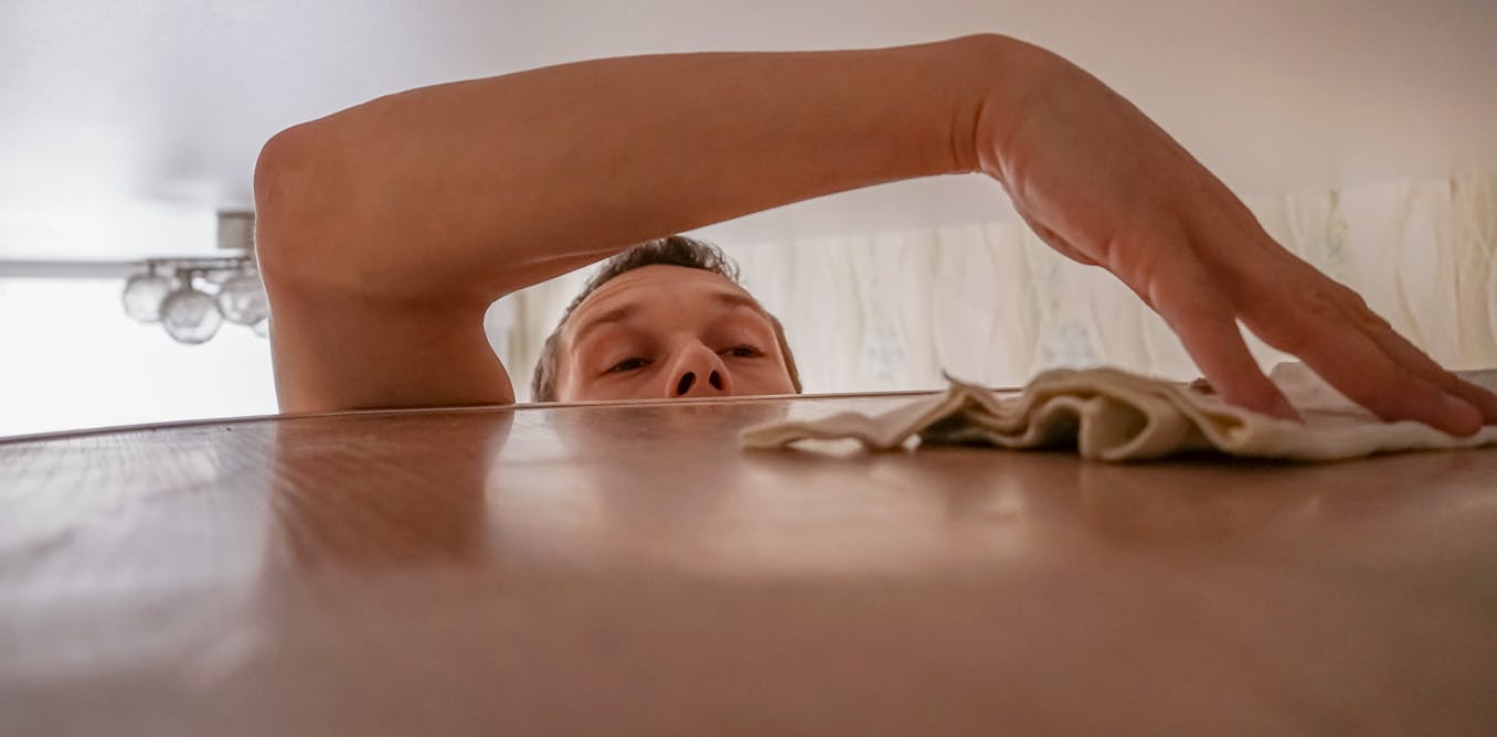 Person wiping dust off a shelf