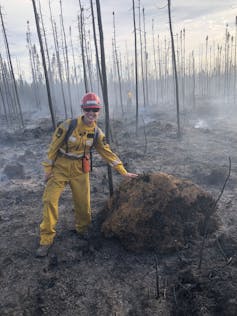 A woman stands next to a pile of moss that remains unaffected by fire.