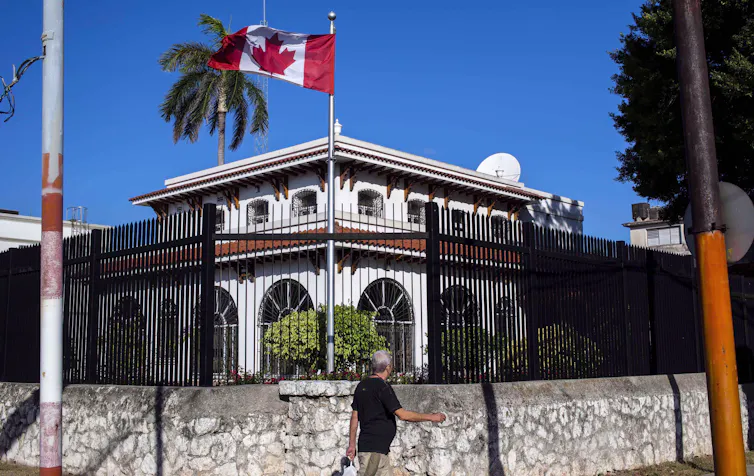 un bâtiment arborant un drapeau canadien derrière une clôture en fer forgé