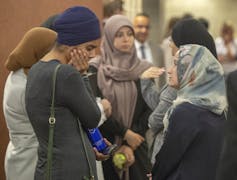Women, some in hijabs, wait to enter a courtroom.
