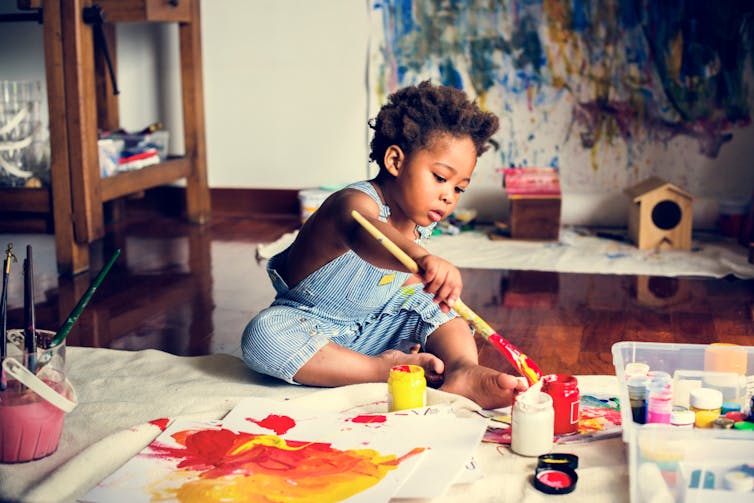 African American toddler painting on a wide sheet of paper in a nice flat