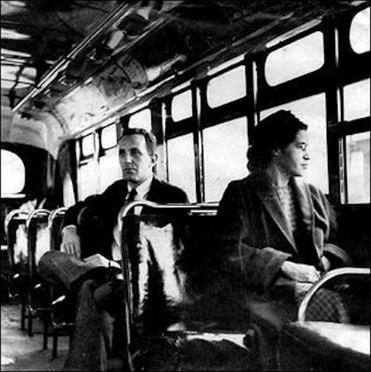 Una mujer negra sentada delante de un autobús.
