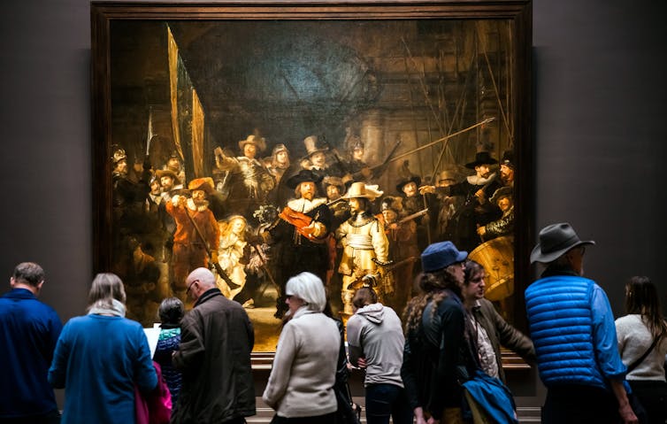 Amsterdam, Netherlands - April, 2017: Visitors watching ‘The Night Watch,’ Rembrandt’s largest and most famous painting in Rijksmuseum’s Gallery. 