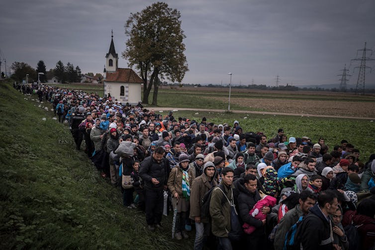 Sergey Ponomarev Migrants walk past the temple as they are escorted by Slovenian riot police to the registration camp outside Dobova Slovenia