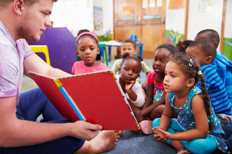 Man showing book to children