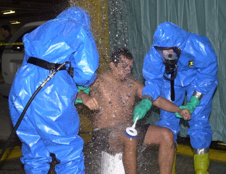 Photo of man being decontaminated.