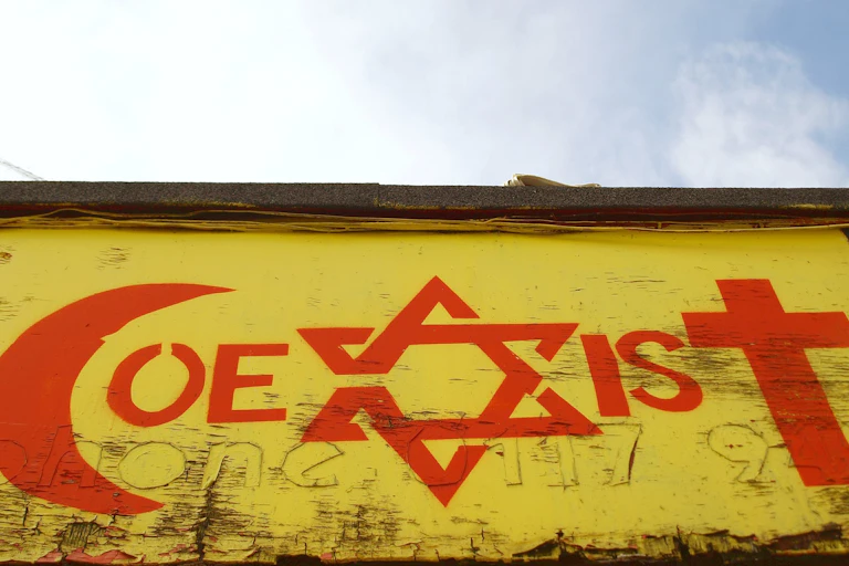 Mural of word "co-exist" with letters c,x and t replaced by religious symbols of Islam, Judaism and Christianity