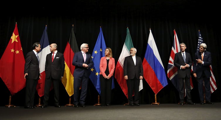 Photo of global leaders from China, France, Germany, Italy, The Netherlands, the United Kingdom and the United States, standing in front of their respective flags.